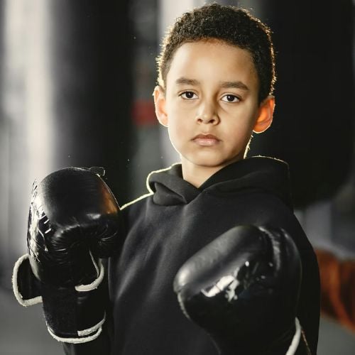 Young boxer in black hoodie and gloves with serious expression